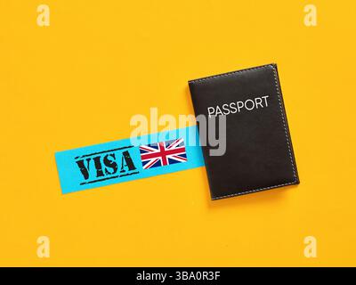 Beantragung eines Visums für das Vereinigte Königreich. Pass und Visum liegen auf gelbem Hintergrund, was auf das Konzept der Reise nach Großbritannien hindeutet. Stockfoto