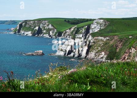 Dramatische Klippen treffen auf das türkisfarbene Meer in diesem malerischen Blick auf die Küste. Die zerklüfteten, weißen Felsformationen werden von üppig grünen Hügeln gekrönt Stockfoto