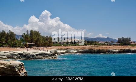 Idyllische Küstenlandschaft mit zerklüfteten Klippen, türkisfarbenem Wasser und einem klaren, sonnigen Himmel mit Wolken. Entspannende und einladende Atmosphäre am Meer Stockfoto