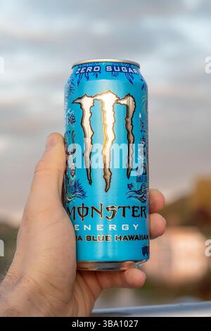 Monster Energy Ultra Blue Hawaiianisches Getränk. Halten Sie den Zero Sugar Energy Drink in der Hand. Sonnenlicht bei Sonnenuntergang beleuchtet die Dose während des Aufenthalts im Freien Stockfoto
