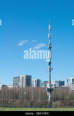 Telekommunikationsturm auf einem Hintergrund der Stadt und des blauen Himmels Stockfoto