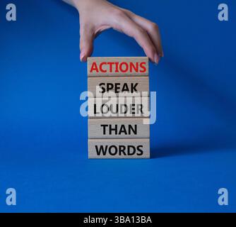 Taten sprechen lauter als Wörter. Holzblöcke mit Worten Aktionen sprechen lauter als Worte. Wunderschöner blauer Hintergrund. Geschäftsmann Hand. Geschäftsleute Stockfoto