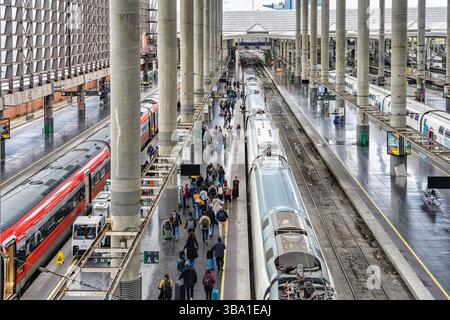 Madrid, Spanien - 10. März 2025: Geschäftiger Tag am Bahnsteig des Bahnhofs Atocha mit abfahrenden Fahrgästen und modernen Hochgeschwindigkeitszügen. Stockfoto