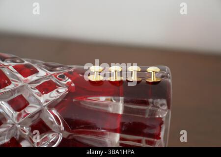 Die goldfarbenen Knöpfe befinden sich auf der roten Vase mit dem unscharfen Hintergrund. Stockfoto