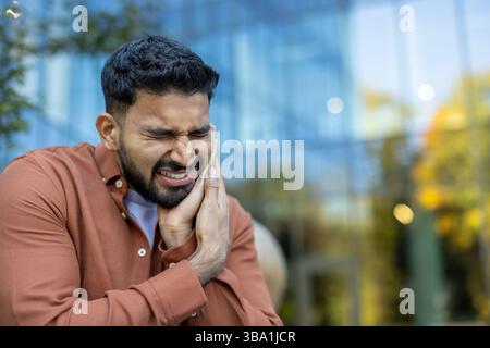 Ein indianer leidet unter starken Zahnschmerzen, er hält sein Gesicht unter Schmerzen und Unwohlsein. Stockfoto