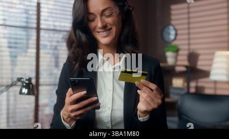 Glückliche kaukasische Frau hält Handy Smartphone Bank Kreditkartenzahlung Online-Einkaufsbestellung weibliches Mädchen zahlen Geschäftsfrau Angestelltes Büro Stockfoto