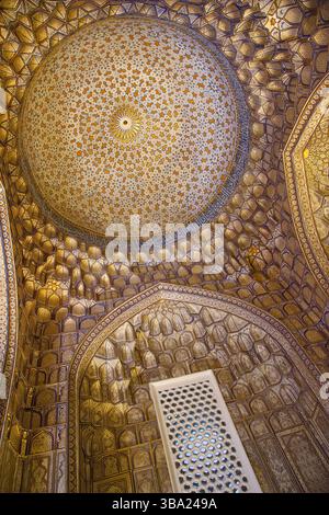 Blick nach oben auf die kunstvoll verzierte und vergoldete Innendecke einer Kuppel in der Nekropole Shah-i-Zinda in Samarkand, Usbekistan Stockfoto