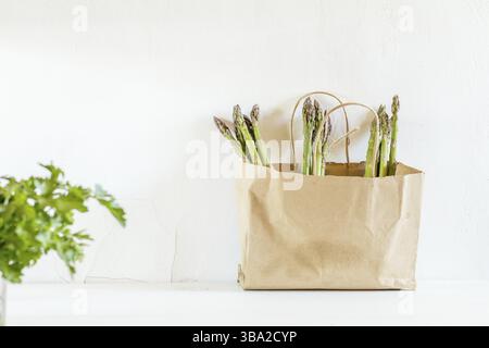 Frische Spargel in einer Papiertüte auf weißem, rissigem Hintergrund. Kopierbereich Stockfoto