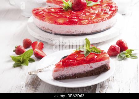 Erdbeerkuchen auf weißem Holzteller mit Minzeblätter Stockfoto