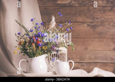 Wildblumen in weißer Keramik Krug und Tassen auf Tablett Stockfoto