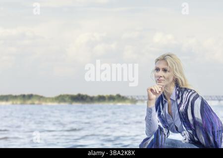 Blonde, lustige, glückliche, hübsche romantische Frau im Park in der Nähe des Flusses. Sonniger Tag Stockfoto