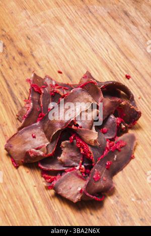 Basturma: Getrocknetes Schweinefleisch mit Pfeffer auf dem Holzbrett Stockfoto