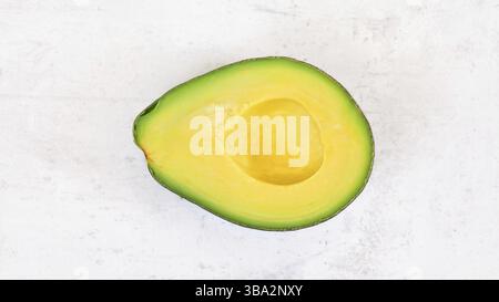 Avocadohälfte, mit hellgelbem Zellstoff auf weißem Steinbrett, Foto von oben, Liptovsky Hradok, Slowakei, Europa Stockfoto
