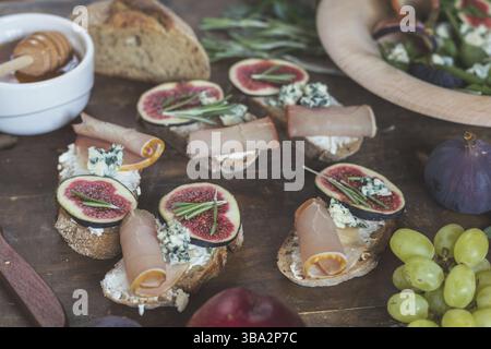 Einfache Diät Salat mit Rucola, Feigen und Blauschimmelkäse auf ein braunes Holz- Oberfläche. Sandwiches mit Ricotta, frische Feigen, Prosciutto, Rosmarin und blauen Käse Stockfoto