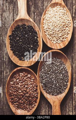 Chia- und Leinsamen, weißer und schwarzer Sesam in Holzlöffeln Stockfoto