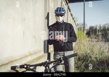 Radfahrer in Gesichtsmaske wegen Smog in der Stadt. Fahrradkurier, der eine Lieferung macht. Mann mit covid-19-Coronavirus-Maske. Radfahrer in Verschmutzungsmaske von Bu Stockfoto