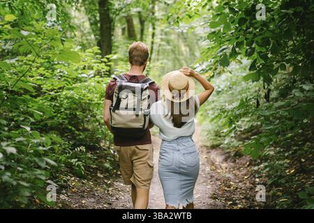 Ein Paar, das Hände hält und im Wald läuft, Rückansicht. Abenteuer, Reisen, Tourismus, Wanderung, Menschen. Rückansicht von zwei Personen, die beim Gehen einen Rucksack tragen Stockfoto