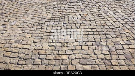 Steinpflaster in der Perspektive. Steinpflasterstruktur. Granit Kopfsteinpflaster Hintergrund. Abstrakter Hintergrund eines Kopfsteinpflasters close-u Stockfoto