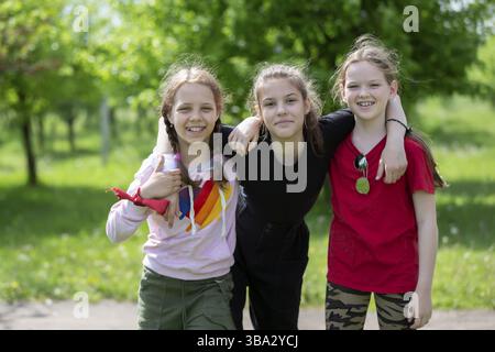 Mai 2021. Weißrussland, Gmel. Kinderfeier. Drei Freundinnen Mädchen im mittleren Schulalter spielen draußen, schauen in die Kamera und lachen Stockfoto