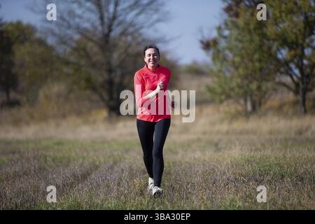 Fröhliche sportliche ältere Frau. Positive ältere Frau macht einen Jogg. Porträt einer sportlichen älteren Frau im Park Stockfoto