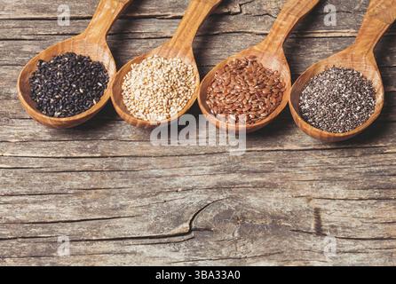 Chia- und Leinsamen, weißer und schwarzer Sesam in Holzlöffeln Stockfoto