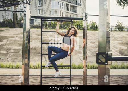 Attraktive passen junge Frau im Sport tragen Rest auf der Straße trainieren. Die gesunden Lebensstil in der Stadt. Street Portrait starke Frau posiert im Fitnessstudio Stockfoto