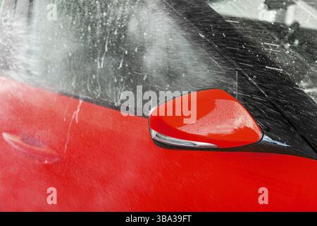Seitenspiegel von hellrotem Auto gewaschen in Selbstbedienungswaschanlage, Wasser auf das Glas sprühen, Liptovsky Mikulas, Slowakei, Europa Stockfoto