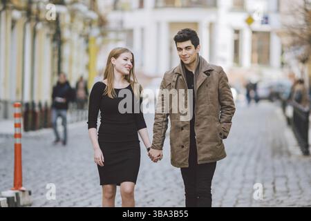Städtische moderne junge Liebe Paar romantische reden reden, halten sich an den Händen auf ein Datum. Junge multikulturelle Türkische brunette und kaukasischen Paar auf Stockfoto