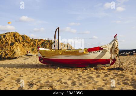 Traditionelles altes Holzfischboot am felsigen Strand. Reisekonzept. Costa Brava, Spanien. Angelboot ruhen am goldenen Sandstrand mit Blick auf die blu Stockfoto
