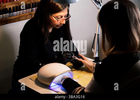 Schönheits- und Nagelsalon. Professionelle Maniküre, nagellack für einen Kunden streichen. Stockfoto