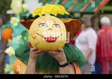 Kreativ dekorierte Halloween-Kürbisse in menschlichen Händen. Ein nettes Gesicht mit einem Lächeln auf einem Kürbis. Karnevalskostüm für die Herbstferien Stockfoto