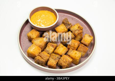 Knusprig gebratene Schweinebauchbacken und scharfe Sauce mit weißem Hintergrund Stockfoto