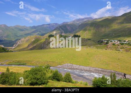 Militärische georgianische Straße. Eine wunderschöne Berglandschaft mit einem fließenden Fluss und einem kleinen Dorf Stockfoto