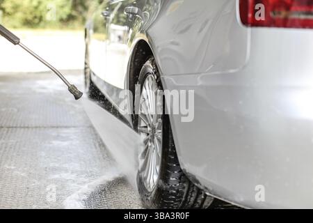 Seiten- und Hinterrad des silbernen Autos, gewaschen in Selbstbedienungswaschanlage, Wassersprühen von Hochdruckdüse, Liptovsky Mikulas, Slowakei, Europa Stockfoto
