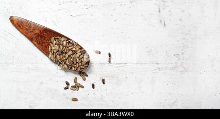 Kleiner Holzlöffel mit gesegneten Mariendistelsamen - Silybum marianum - auf weißem steinähnlichem Brett, Blick von oben, Platz für Text rechts, Liptovs Stockfoto