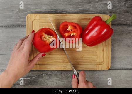 Blick auf die Tischplatte, Frauenhände schneiden roten Paprika mit Küchenmesser auf Schneidebrett, Liptovsky Hradok, Slowakei, Europa Stockfoto