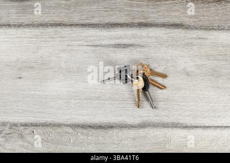 Schlüssel am Schlüsselanhänger auf laminatgrauem Holzboden gefallen Stockfoto