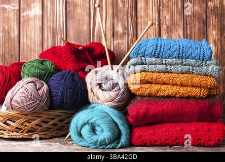 Farbfäden, Stricknadeln und Kleidung auf dem Holztisch Stockfoto