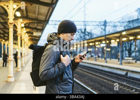 Sopot fast Urban Railway Station: Junger Mann steht und wartet auf dem Bahnsteig. Touristenfahrten mit dem Zug. Porträt Des Kaukasischen Männers In Bahn Tr Stockfoto