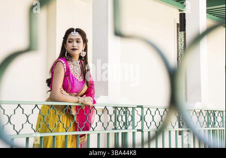 Rosa und Gelb Indianer Kostüm schönes Mädchen, Gesicht teilweise mit Saree bedeckt. Porträt einer traditionellen Frau im Saristil Stockfoto