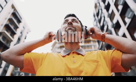 Mann mit Sicherheitsausrüstung Gehörschutz. Mitarbeiter mit geräuschreduzierenden Gehörschutzschützern oder Ohrenschützern. Baumeister setzt auf schützen Ohren Stockfoto