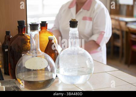 Glaskolben auf einem Labortisch. Retro Apotheke Container auf dem Hintergrund der Laboratory Assistant Stockfoto