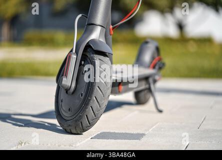 Elektroroller auf gefliestem Steinpflaster geparkt - Nahaufnahme am Vorderrad, Liptovsky Mikulas, Slowakei, Europa Stockfoto