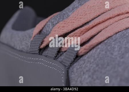 Ein Fragment eines grau Sneaker mit rosa Spitzen hautnah. Sneaker Textur Stockfoto