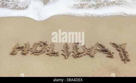 Wort URLAUB geschrieben auf nassem Sand des Strandes, kleiner Fleck mit weißem Meerwasser im oberen Teil, Dipkarpaz, Zypern, Europa Stockfoto