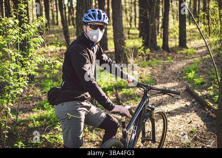 Sport. Mountainbike-Radfahrer fahren auf einer Spur. Mann auf dem Fahrrad trägt Atemschutzmaske mit Hochleistungs-Schutzfilter. Atemschutzmasken. Stockfoto