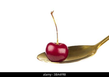Kirschbeeren auf einem goldenen Löffel. Nahaufnahme auf einem weißen Hintergrund von wilden Kirschen. Wunderschönes Jahr Stockfoto