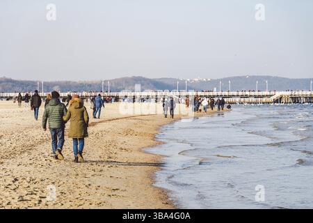 Polen, Sopot, 9. Februar 2020. Leute am Strand in Sopot. Menschenmenge am Strand im Winter. Genießen Sie den Tag im sonnigen Winter in der Nähe des Meeres. Menschen, die entlang laufen o Stockfoto