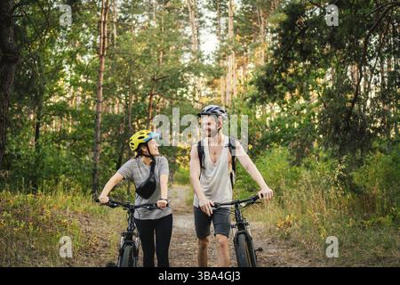 Wunderbares Paar, das im Parkwald auf Fahrrädern fährt. Romantische Fahrt mit dem Fahrrad. Aktives Wochenende. Sportpaare. Radfahrerinnen und Radfahrer. Umweltfreundlicher Transpor Stockfoto
