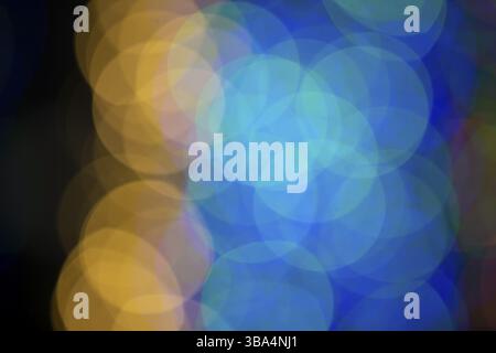 Mehrfarbige große Bokeh-Flecken in Blau und Gelb. Bokeh von einer Weihnachtsgirlande Stockfoto